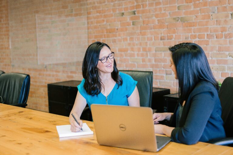 Two Women Talking at Desk